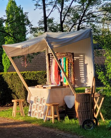 Marktstand mit bunten Tüchern und handgefertigten Accessoires in der Natur.