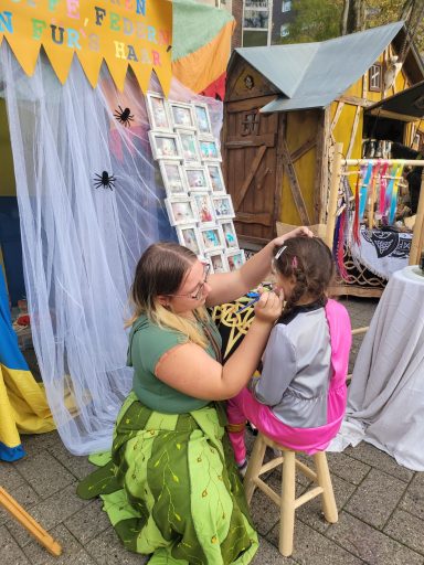 Eine Person frisiert eine andere in einem festlichen, bunten Umfeld.