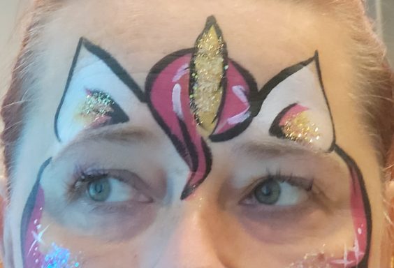 Bunt gestaltetes Gesicht mit einem Einhorn-Design auf der Stirn.