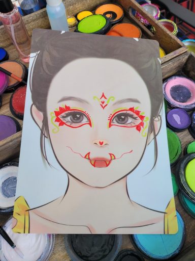 Porträt eines Mädchen mit buntem Gesichtsschmuck und verspielt lächelndem Ausdruck.