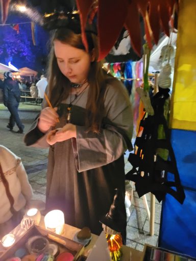 Junge Frau bemalt Accessoires an einem Marktstand im Freien.