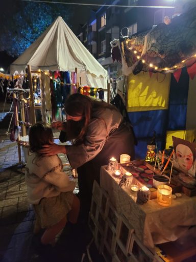 Ein Erwachsener beugt sich zu einem Kind, umgeben von Dekoration und Kerzenlichtern.