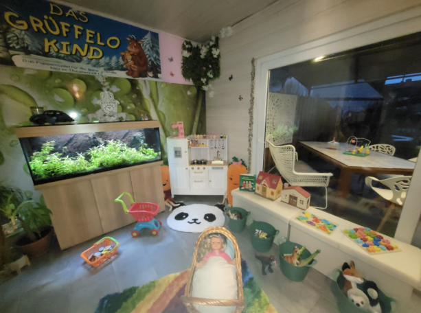 Bunte Kinderecke mit Spielzeug, Aquarium und gemütlichem Sitzbereich.