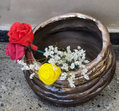 Brauner Körbchen mit roten und gelben Blumen sowie weißen kleinen Blüten.