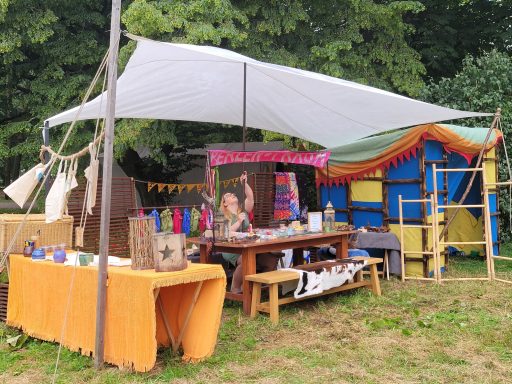 Bunte Marktstände unter einem Zelt mit Tischen und bunten Accessoires.
