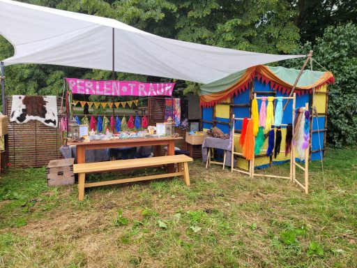 Bunte Marktstand mit Tüchern und einem Holz-Tisch im Freien.