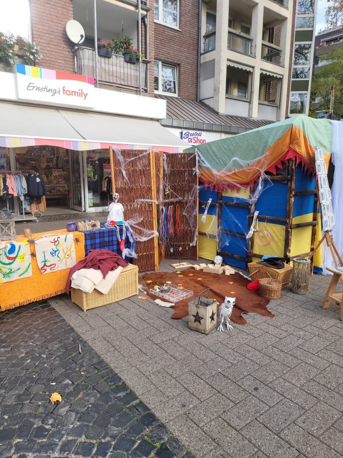 Marktstand mit bunten Stoffen, handgemachten Gegenständen und dekorativen Elementen.
