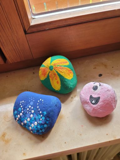 Bunte Steine mit blühendem Muster, Wassertropfen und einem lachenden Gesicht.