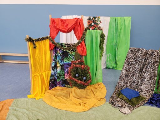 Bunte, textile Kulisse mit verschiedenen Stoffen in Gelb, Rot, Grün und Schwarz.