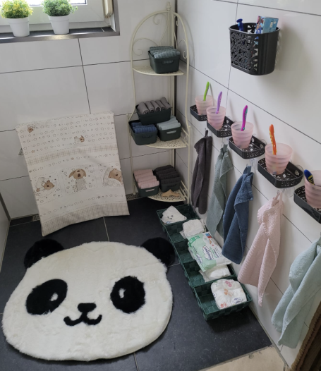 Badezimmer mit einem Pandamotiv-Teppich und Regalen für Handtücher und Pflegeartikel.