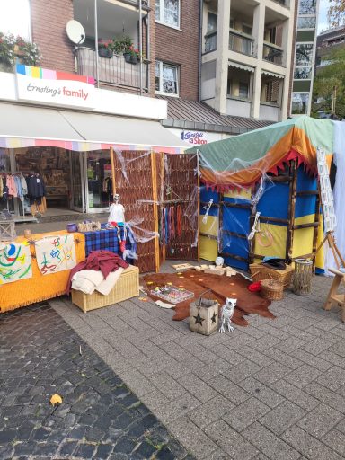 Bunte Marktstände mit Dekorationen und Waren auf einem Platz.